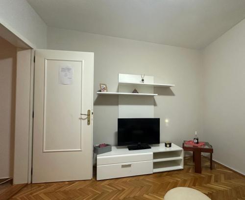 ein Wohnzimmer mit einem Fernseher auf einem weißen Schrank in der Unterkunft Apartman Tiki R Vrnjacka Banja in Vrnjačka Banja