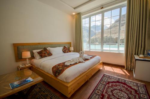 a bedroom with a bed and a large window at The Consorts Hotels & Resorts HUNZA ATTABAD LAKE in Hunza