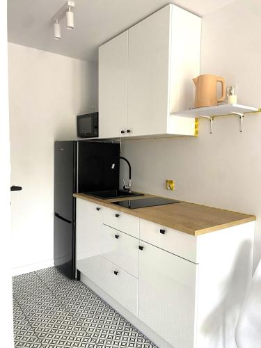 a kitchen with white cabinets and a black refrigerator at SeaSide in Gdańsk