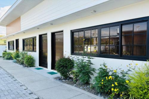 a white building with black windows and plants at Selline Bed and Breakfast in Bacnotan