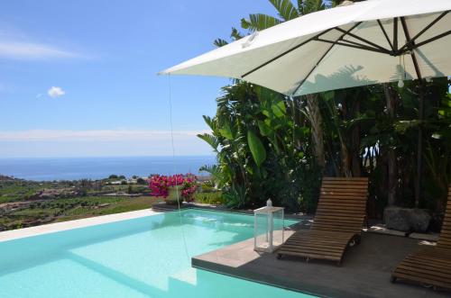 a swimming pool with two chairs and an umbrella at La casa del panorama in Valverde
