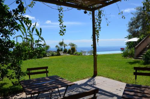a picnic table and benches in a field with the ocean at La casa del panorama in Valverde