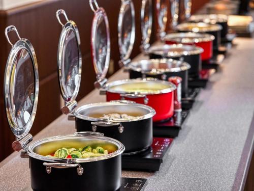 a row of pots of food on a buffet line at Royal Pines Hotel Chiba- Opening in Jan 2025 in Chiba