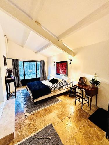 a bedroom with a bed and a desk in a room at La Villa Bohème in Oppède