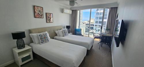 a hotel room with two beds and a balcony at Broadbeach Holiday Apartments in Gold Coast