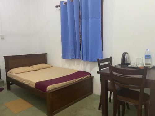 a bedroom with a bed and a desk with a table and chairs at Eagles Eco Lodge - Kandy in Digana