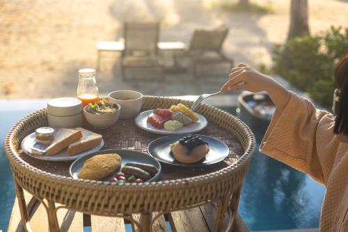 una mujer sentada en una mesa con un plato de comida en Irene Resort Koh Lipe, en Ko Lipe