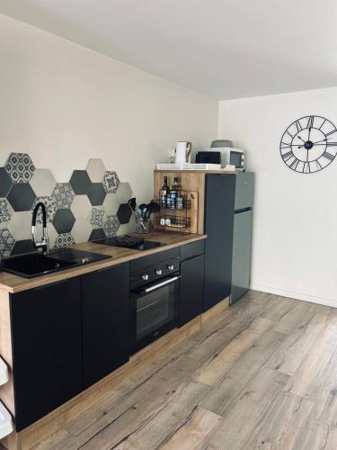 - une cuisine avec des armoires noires et un réfrigérateur noir dans l'établissement Appartement 3 étoiles tout confort et spacieux en campagne bourguignonne, à Mancey