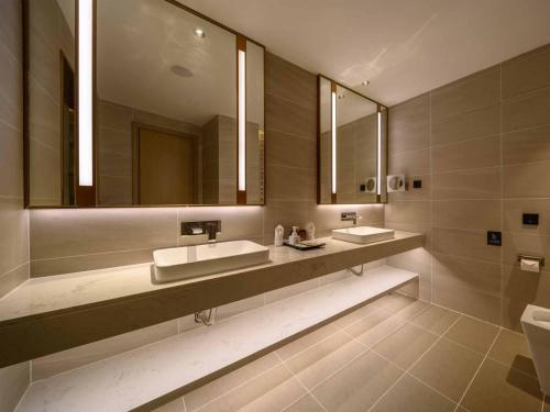 a bathroom with two sinks and two mirrors at Lavande Hotel Dongguan Songshan Lake in Dongguan