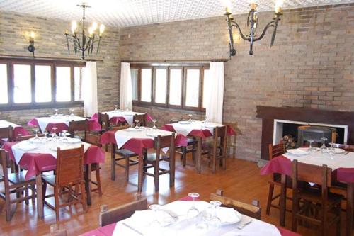 a dining room with tables and chairs and a fireplace at Camping Urbion in Abejar