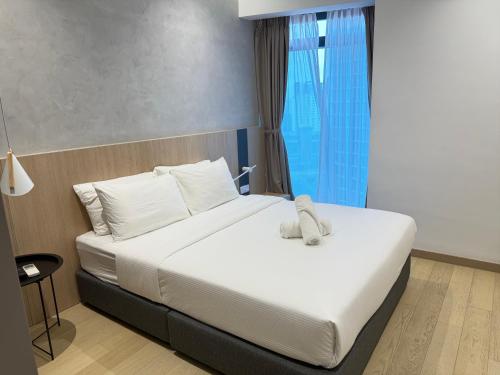 a bedroom with a bed with white sheets and a window at Eaton Residences KLCC By ARMAN in Kuala Lumpur