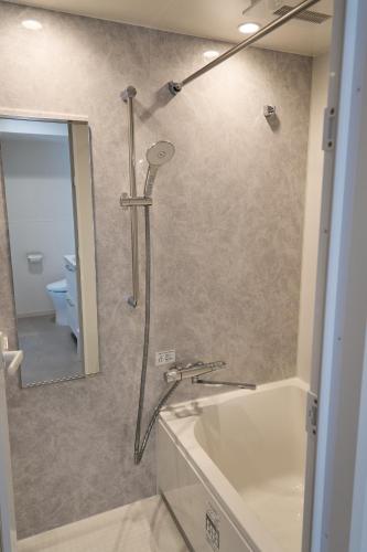 a bathroom with a shower with a tub and a sink at KOTI Hakata in Fukuoka