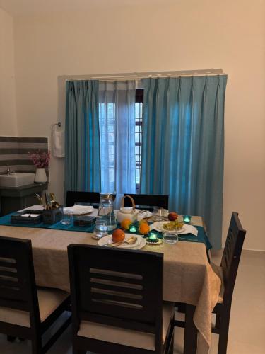 a dining room table with food on it with blue curtains at Azalea Farmhouse, Palmgrove in Jorhat
