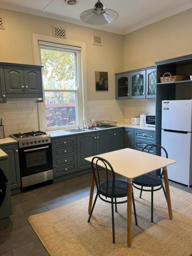une cuisine avec des armoires vertes et une table et des chaises dans l'établissement Kelpie Cottage, Luxe 1930s Stay in the Heart, à Albury
