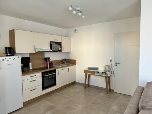une cuisine avec des armoires blanches et un réfrigérateur blanc dans l'établissement T2 Appartement Sunset Lodge à 250 m de la mer, 3 couchages, à Narbonne-Plage