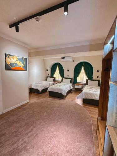 a room with three beds and a rug at Status Inn Hotel in Samarkand