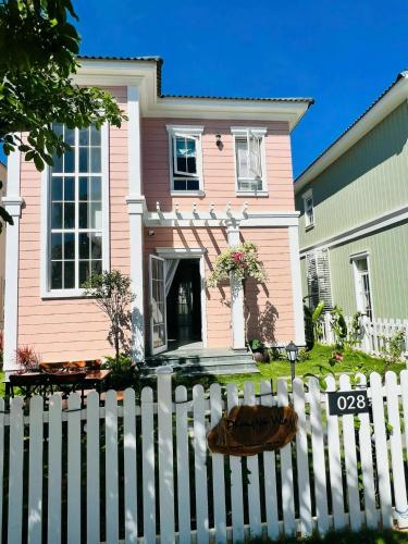 a white picket fence in front of a pink house at Holiday Villa Novaworld Phan Thiet in Phan Thiet