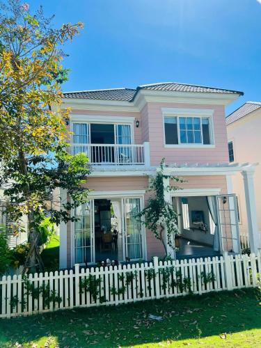 a pink house with a white picket fence at Holiday Villa Novaworld Phan Thiet in Phan Thiet