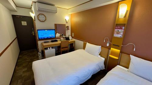 a room with two beds and a desk with a computer at Toyoko Inn Shin-yokohama Ekimae Honkan in Yokohama