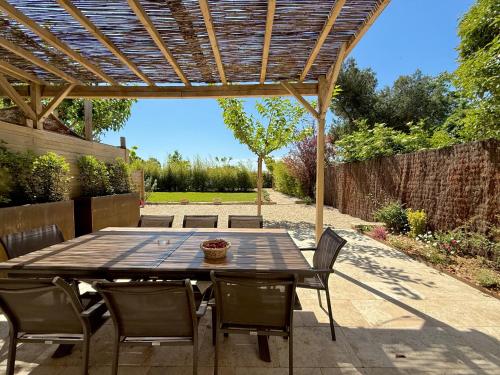 un patio avec une table et des chaises sous une pergola en bois dans l'établissement Gîtes Amour de Provence, à Châteaurenard