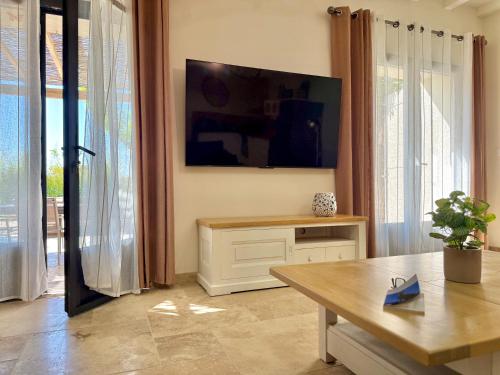 a living room with a table and a tv on the wall at Gîtes Amour de Provence in Châteaurenard