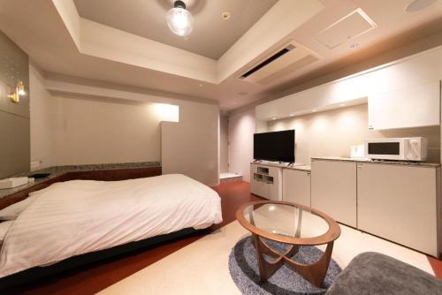 a bedroom with a bed and a table and a tv at ホテルネオワカバ in Tsuchiura