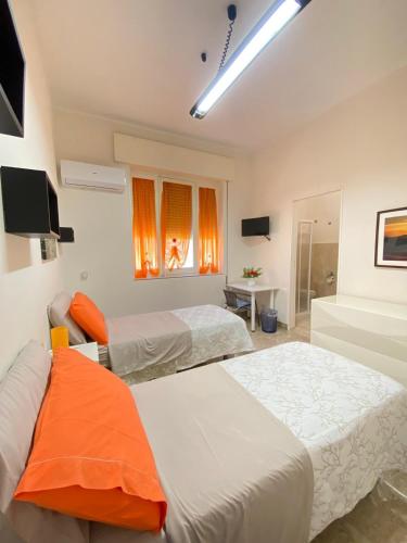 two beds in a room with orange curtains at Valderice Rio Apartments in Valderice