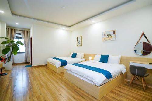 a hotel room with two beds and a desk at Ngo - The Gallery Hotel Dalat in Da Thanh