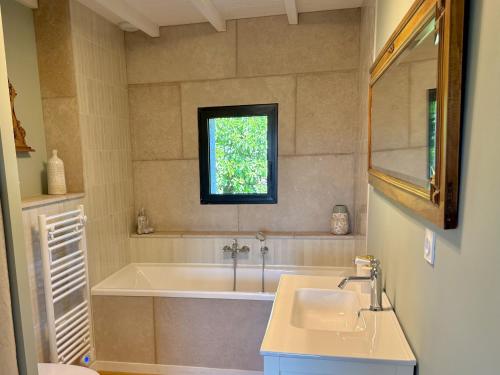a bathroom with a tub and a sink and a window at Gîtes Amour de Provence in Châteaurenard