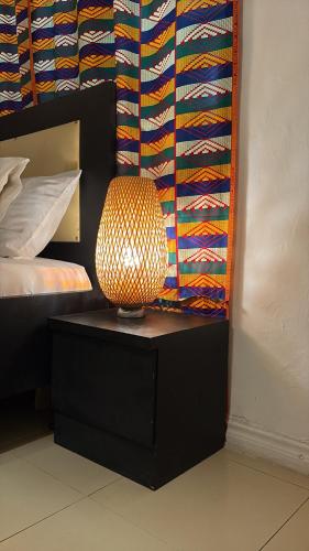 a lamp sitting on a table next to a bed at African Treasure Beach Resort in Kokrobite