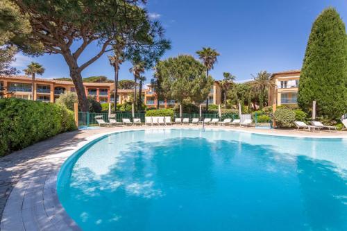 een groot zwembad met stoelen en bomen bij Résidence Pierre & Vacances La Pinède in Hyères