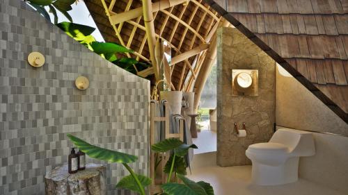 a bathroom with a toilet and some plants in it at Mandala Eco Resort Lombok in Selong Belanak