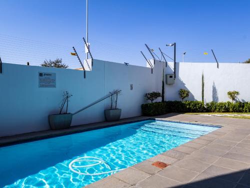 a swimming pool next to a white wall at Thetan's Home Away From Home in Midrand