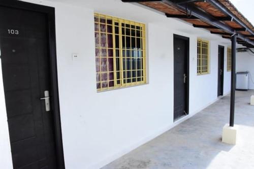 a white building with black doors and yellow windows at RDS Guest House Bypass in Āmbūr
