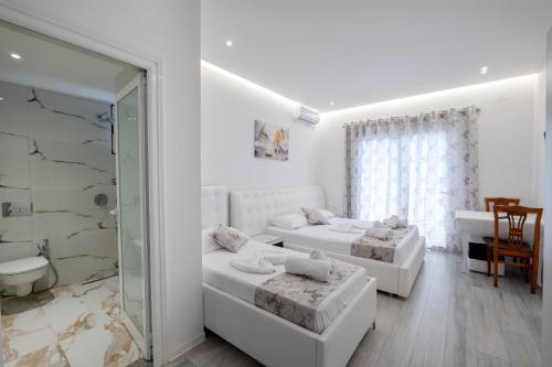 a white room with two beds and a bathroom at Vila Irdi in Ksamil