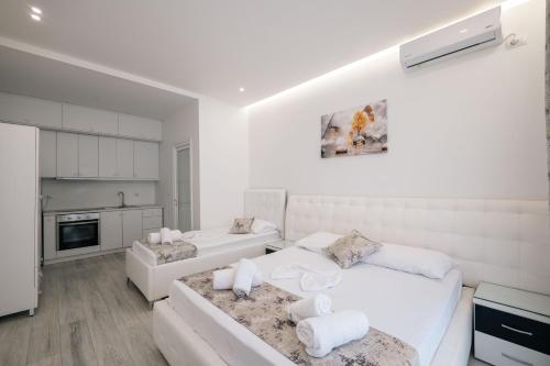 a white bedroom with two beds and a kitchen at Vila Irdi in Ksamil