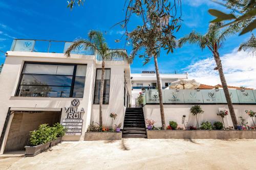 a white house with palm trees in front of it at Vila Irdi in Ksamil