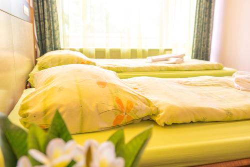two beds in a bedroom with yellow sheets and flowers at Hotel Gorna Banya in Sofia