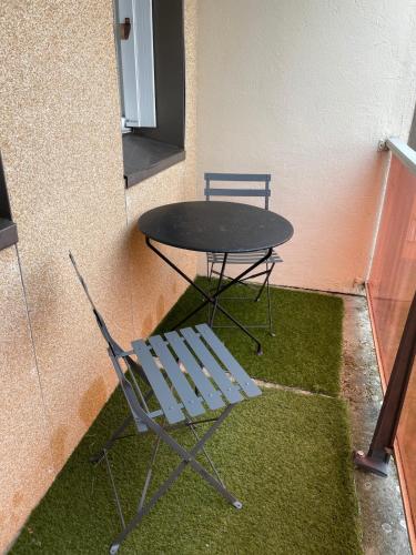 une table et une chaise assises à côté d'un mur dans l'établissement Spacious apartment in Guingamp, à Guingamp