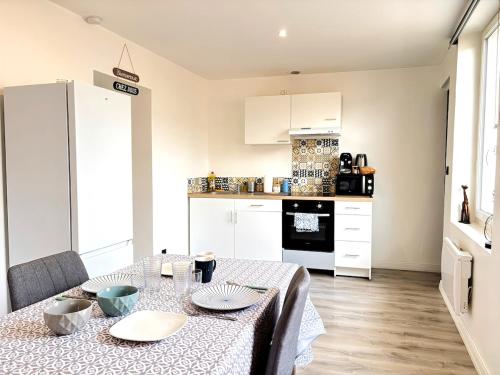 une cuisine avec une table et des placards blancs dans l'établissement Urban Chic Studio 10 min de la gare, à Roanne