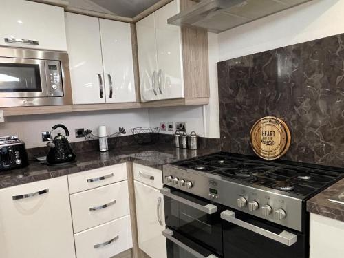 a kitchen with a stove and a microwave at Romney Lodge in New Romney