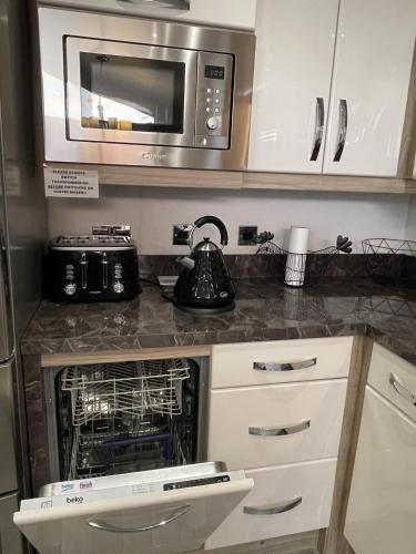 a kitchen with a stove and a microwave at Romney Lodge in New Romney