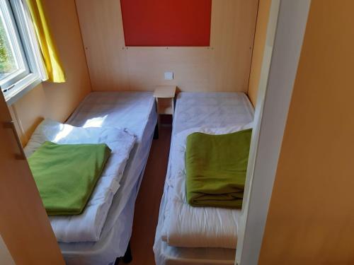 une petite chambre avec deux lits et une fenêtre dans l'établissement Camping le Convivial Mobil home 2 chambres 24m2, à Saint-Martial-de-Nabirat