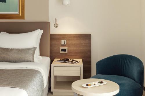 a hotel room with a bed and a blue chair at Hotel Bellevue in Mali Lošinj