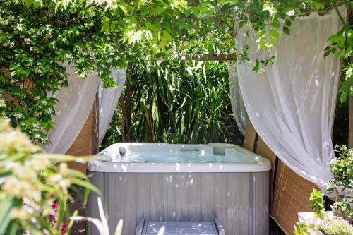 a hot tub in a garden with curtains at Hôtel La Villa Sainte Valérie Adults Only in Juan-les-Pins