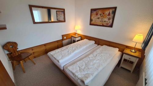 a bedroom with a bed and a chair and a mirror at Rothornblick in Arosa