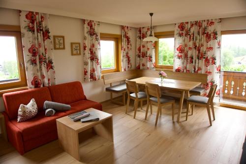 a living room with a red couch and a table at Pension Trillerhof in Ramsau am Dachstein