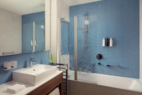a bathroom with a sink and a shower with blue tiles at Hotel Bellevue in Mali Lošinj