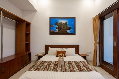 a bedroom with a bed and a picture on the wall at Om Villas Kedungu in Tanah Lot