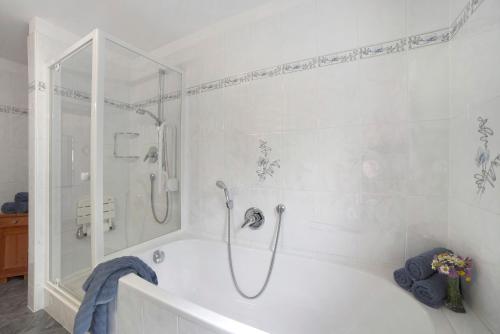 a white bathroom with a shower and a tub at Hienerhof in Moso